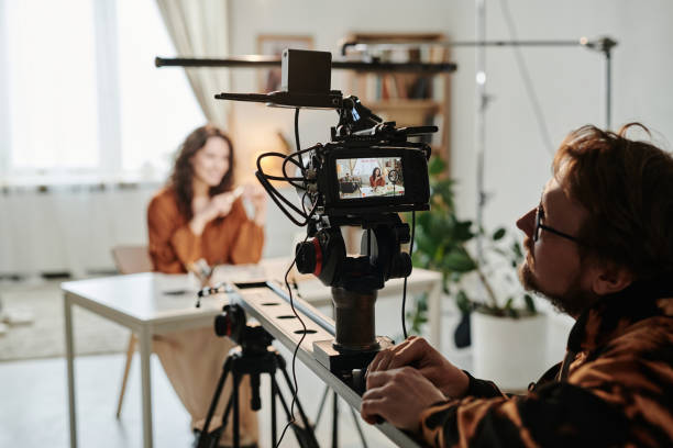 istock Young cameraman adjusting focus and other options of video camera 1394939980