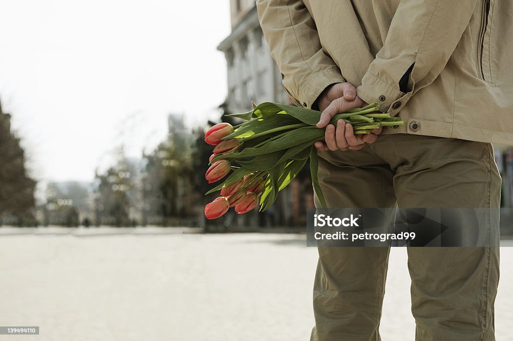 A man standing on the streets holding a holding some tulips Young man is waiting for his girlfriend with tulips Dating Stock Photo