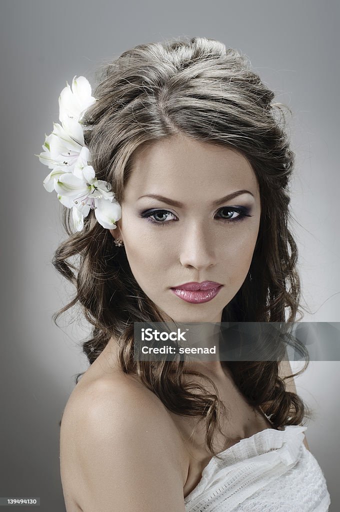 Bride wearing a flower headpiece and curly hair portrait of beautiful bride with flowers in hair on grey 20-29 Years Stock Photo