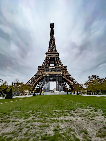 Low angle view of Eiffel tower in Paris on cold spring day with dramatic sky and clouds background. Touristic travel banner with large copy space.