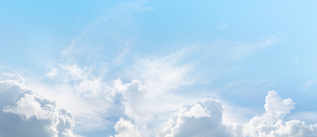 White clouds in a blue sky in summer. Panoramic skyscape in 1:3 format.