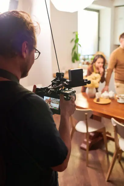 Young operator or videographer with videocamera shooting cooking masterclass or advertisement of homemade meal or pastry
