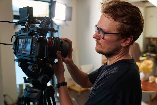 istock Young videographer or cameraman adjusting focus of his video camera 1394944098