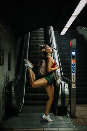 Urban girl doing dance move at the bottom of the escalators