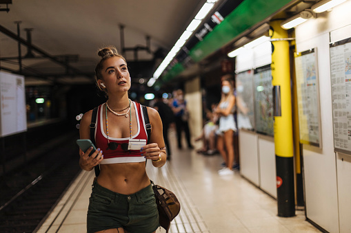 The girl walks through the subway station, looking for a departure schedule