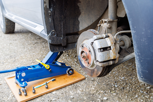 the hub of the front right wheel of a jacked car with a brake disc and pads during a tire change.