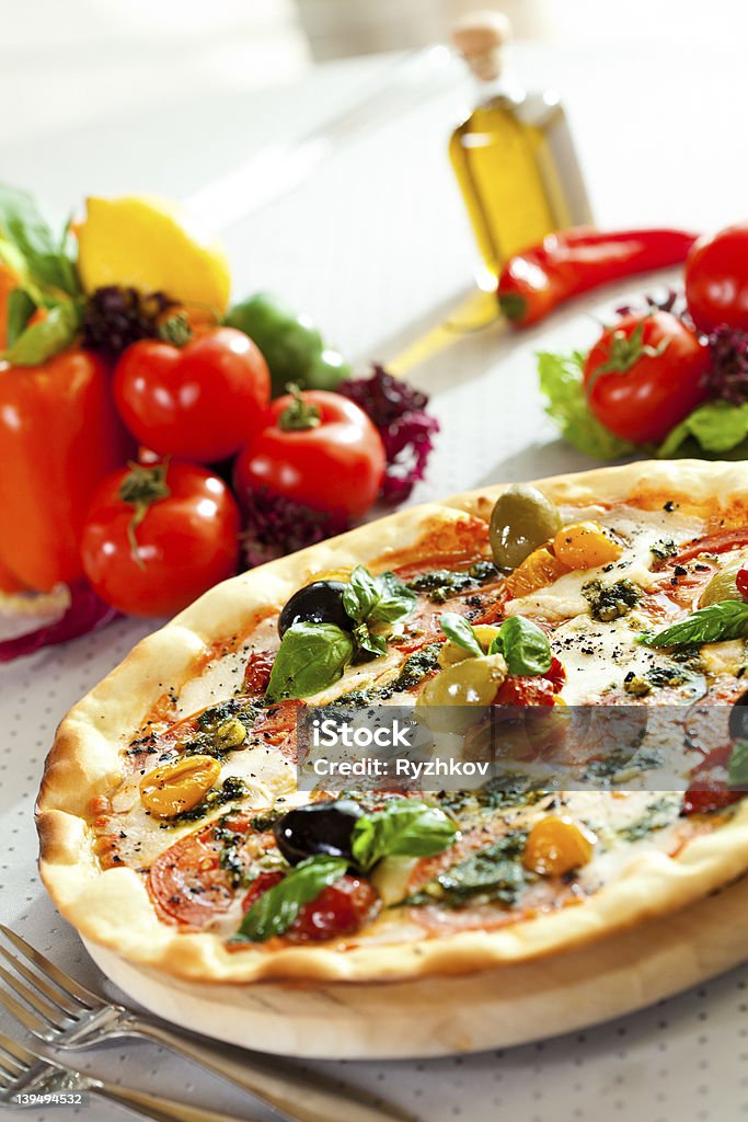 Pizza Dinner Pizza with Mozzarella Cheese, Fresh Tomato and Pesto Sauce. Served at Restaurant Table Baked Stock Photo