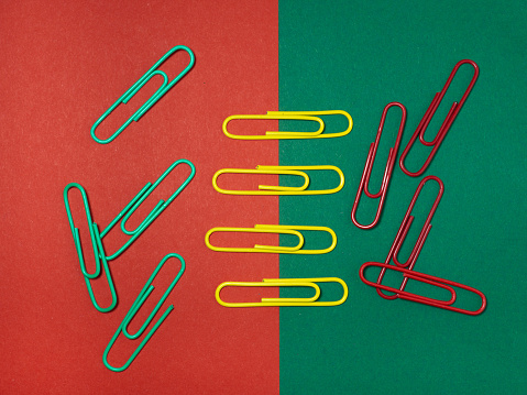 Colored paper clips on paper. Office supplies. Business goods. Colorful office supplies.