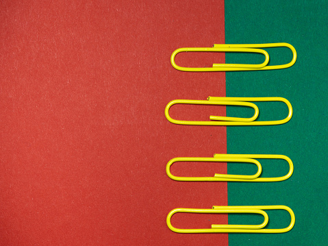 Colored paper clips on paper. Office supplies. Business goods. Colorful office supplies.\
