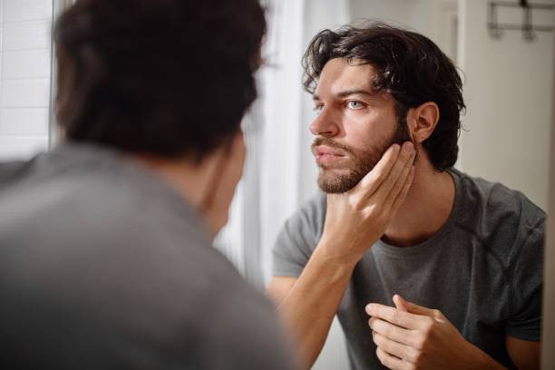 istock Man applying serum to his face 1394951462