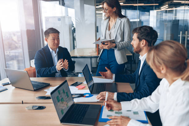 istock Beautiful business people are using gadgets, talking and smiling during the conference in office 1394952079