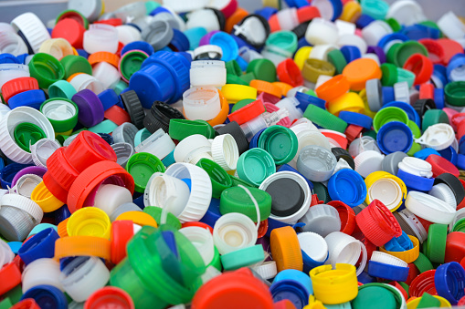 Lots of colorful plastic lids from bottles, discarded waste collected for recycling, environmental protection and sustainable lifestyle concept, full frame background, copy space, selected focus