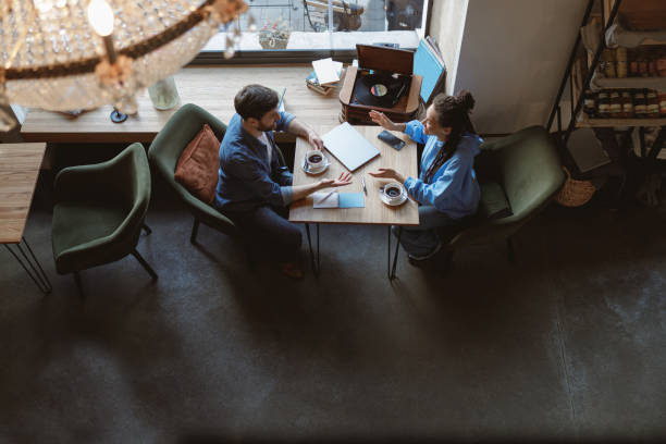 istock View from above on mixed-races young friends or colleagues talking at table with coffee in cafe. 1394955461