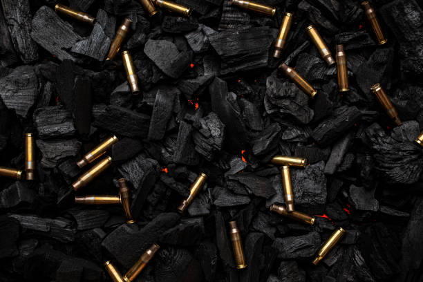 istock Empty shells from weapons on black smoldering coals. Consequences of the war. Dark background. 1394958863
