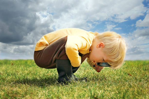 Little Boy Exploring Nature Outside with Magnifying Glass stock photo