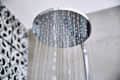 Modern shower with falling water drops in bathroom, closeup