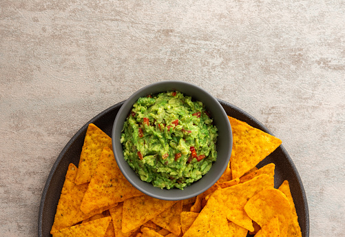 Mexican corn chips nachos with avocado red pepper sauce, top view, copy space
