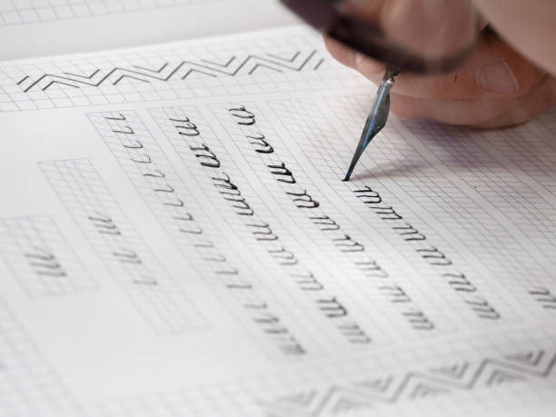 istock Close-up pupil's hands are writing calligraphy in a notebook. Schoolboy calligraphy performs a task at the workplace. Concept of children's education, teaching knowledge, skills and abilities. 1394967046