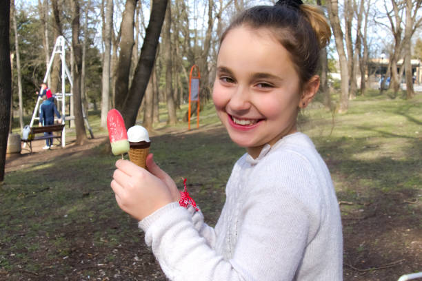 A teenage girl holding ice cream while on a nature walk, close-up stock photo