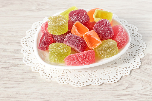 On a white plate, multi-colored jelly delicious marmalade with a fruity taste.