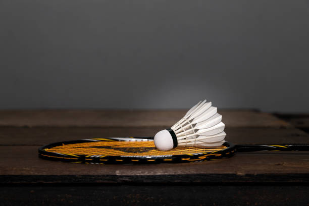 Closeup shot of white badminton shuttlecock and racquet on wooden floor. stock photo