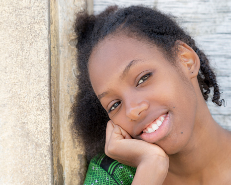 Portrait of a natural beauty sitting in front of her house, eighteen years old, smiling teenage girl, natural Afro hairstyle