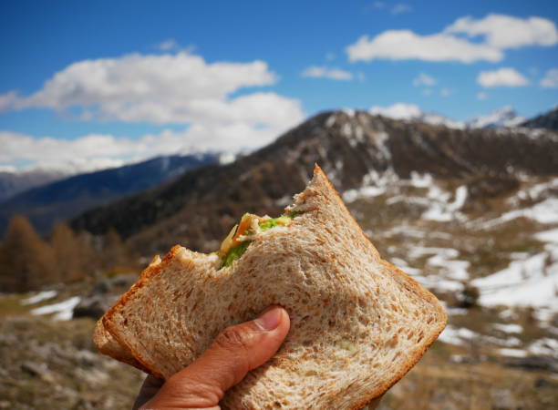 крупный план бутерброда туриста с заснеженной горой на заднем плане - food mountain стоковые фото и изображения