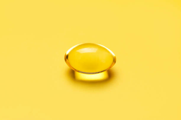 Capsules pill with vitamin D on yellow background close-up. Fish oil, Omega, Omega-3, dietary supplement, sunshine vitamin. Healthy lifestyle, medicine, cosmetology, diet. Pharmaceutical concept Capsules pill with vitamin D on yellow background close-up. Fish oil, Omega, Omega-3, dietary supplement, sunshine vitamin. Healthy lifestyle, medicine, cosmetology, diet. Pharmaceutical concept. cod liver oil fish oil vitamin a pill stock pictures, royalty-free photos & images