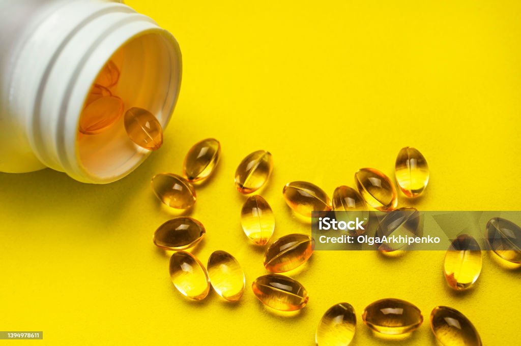 Capsules pill with vitamin D poured out of white plastic packaging on yellow background. Fish oil, Omega, Omega-3, dietary supplement, sunshine vitamin. Healthy lifestyle, medicine, cosmetology, diet Capsules pill with vitamin D poured out of white plastic packaging on yellow background. Fish oil, Omega, Omega-3, dietary supplement, sunshine vitamin. Healthy lifestyle, medicine, cosmetology, diet. Division 3 Stock Photo