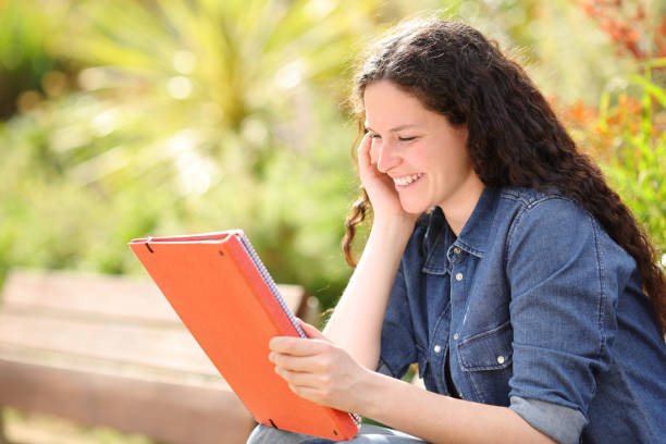 istock Happy woman in a park studying reading notes 1394988284