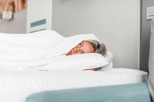 istock Frightened depressed sad middle aged woman lying alone on bed 1394989318