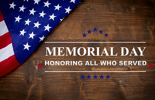 Memorial Day written on a dark wood background, with an American flag.