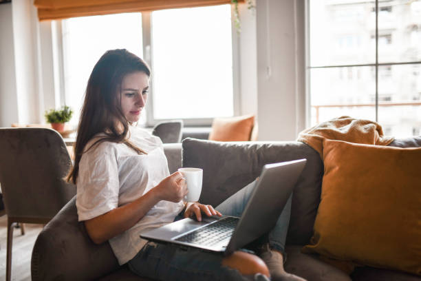 istock Cute Female Surfing The Net On Laptop While Drinking Hot Coffee 1394989648