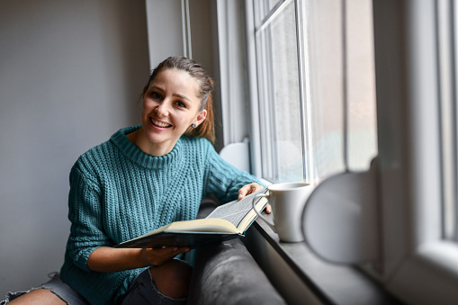 Female Surprised By Story Plot In Book While Enjoying It With Cup Of Coffee