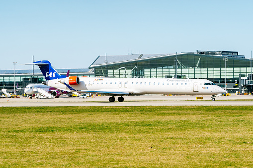 Bombardier Regional Jet 900 of SAS airlines taxiing towards terminals in Gdansk Lech Wałęsa international airport. Cloudy sky on the background.