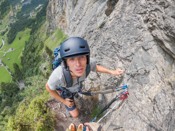 istock Male climber overhanging on wall looking up at camera 1394989884
