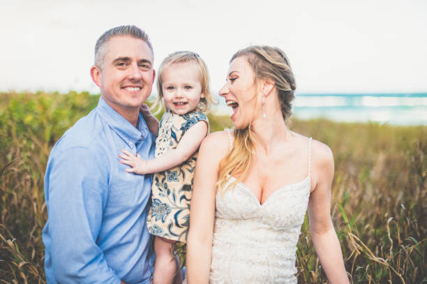 Beautiful bride and groom with their baby daughter at their destination wedding outdoors in an affectionate family portrait Beautiful loving couple getting married outdoors bride hugging father on wedding day stock pictures, royalty-free photos & images