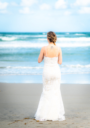 Beautiful young bride on the beach in wedding dress