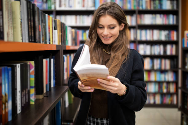 istock Woman reading a book at the library 1394993386