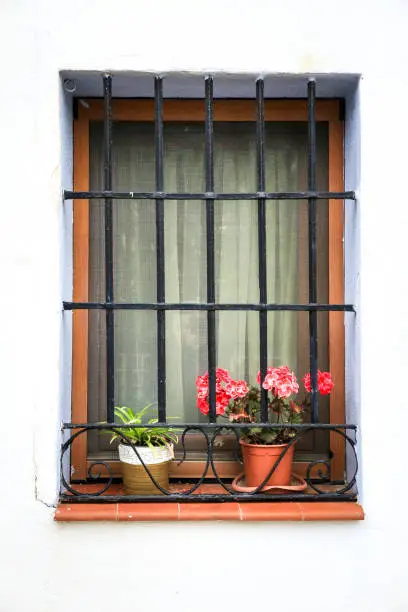 Photo of Whitewashed facade with window with forged metal grill