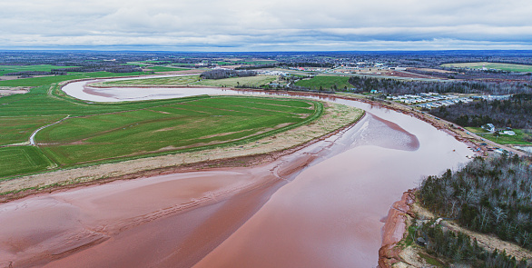 Aerial drone view of a tidal river lined with farmland.