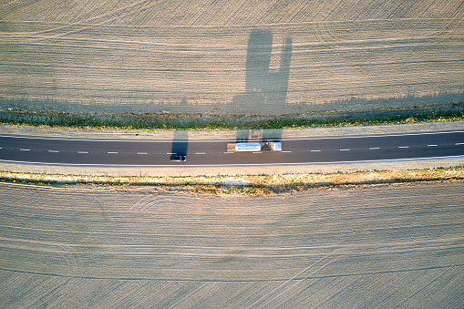 Aerial view of intercity road with fast driving cars at sunset. Top view from drone of highway traffic in evening.