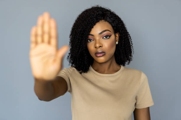 istock African-American female security guard showing stop gesture on light background 1394997205
