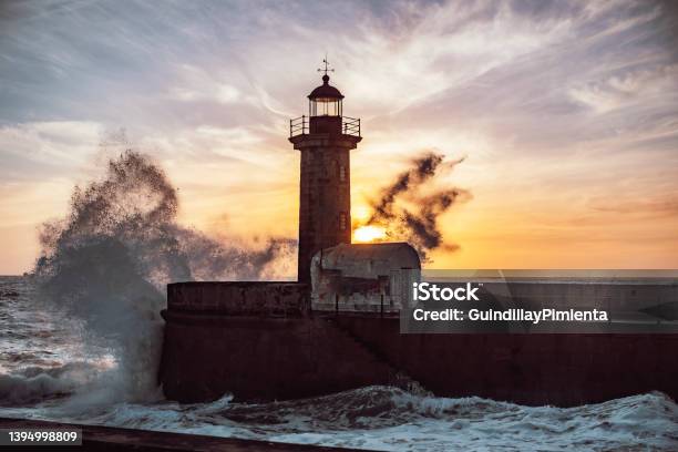 Waves Of The Sea Breaking Over The Porto Lighthouse With The Sunset In The Background Stock Photo - Download Image Now