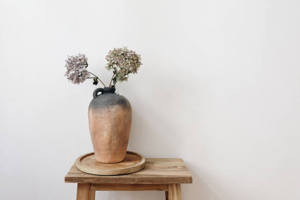 istock Elegant minimal summer, fall still life photo. Rustic clay vase, pitcher with hydrangea flowers on old wooden stool, console table. White wall background. Empty copy space. Elegant interior, lifestyle 1395001381
