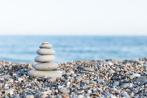Round stones lie on top of each other in a column on the seashore on a sunny summer day. The concept of order and tranquility