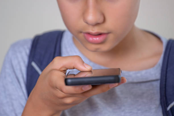 Teenage boy hold smart phone talking through microphone, using cell phone voice recognition function online, sending record voice message.