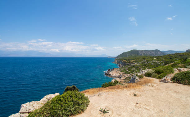 the coast of bright blue Mediterranean Sea and a cliff in green trees stock photo