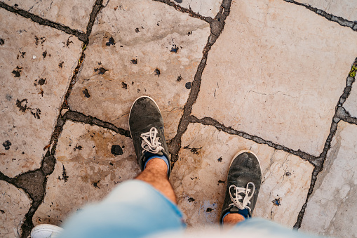 Male feet on cobblestone, personal perspective.