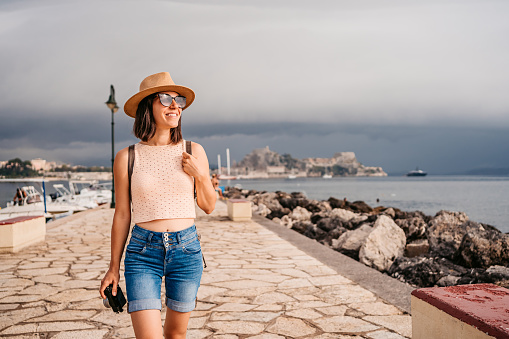 Beautiful young female tourist walking on the coastline of Corfu Town, Greece.